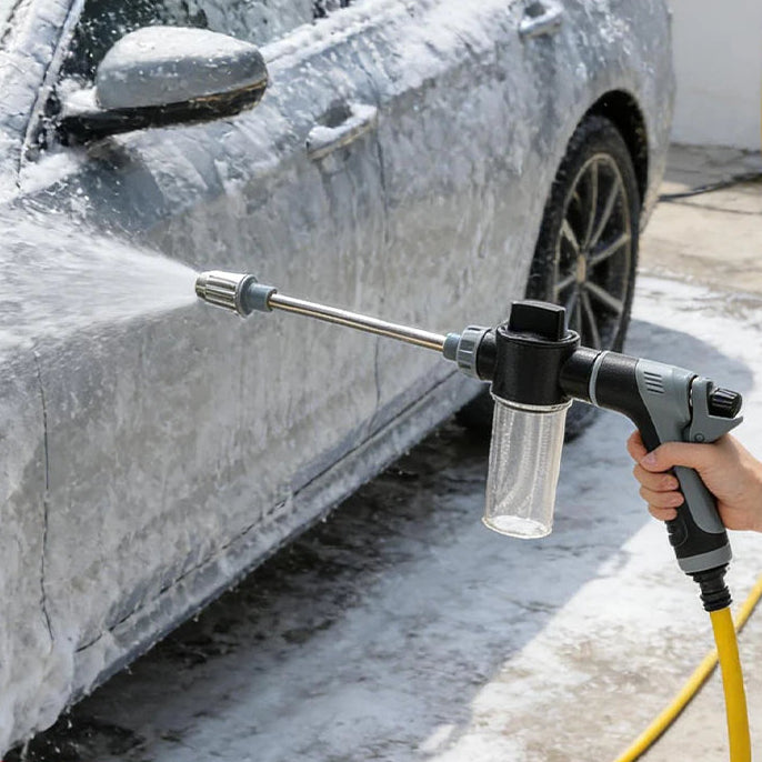 Hand spraying thick snow foam onto a silver car door with the Rotating Foam Wash Gun connected to a yellow hose