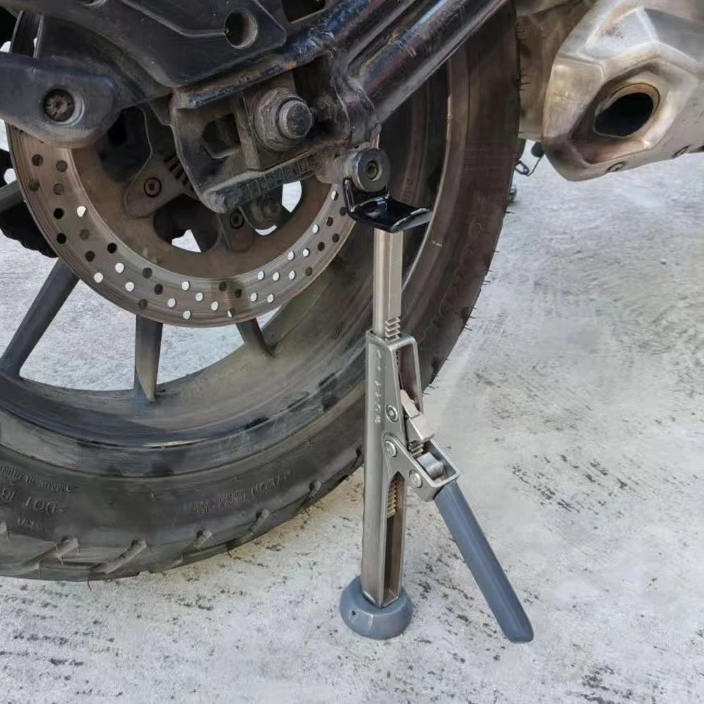 Motorcycle Ratchet Lift Stand positioned under a motorcycle rear axle beside the brake disc and exhaust