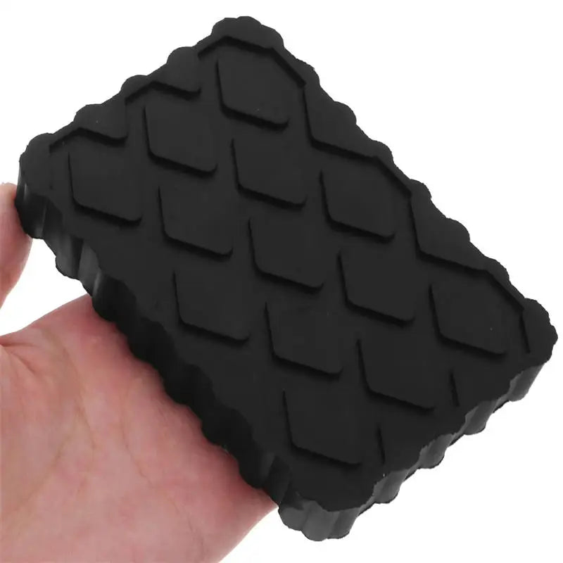 Hand holding a black rubber Heavy-Duty Jack Pad showing the anti-skid diamond tread grip surface