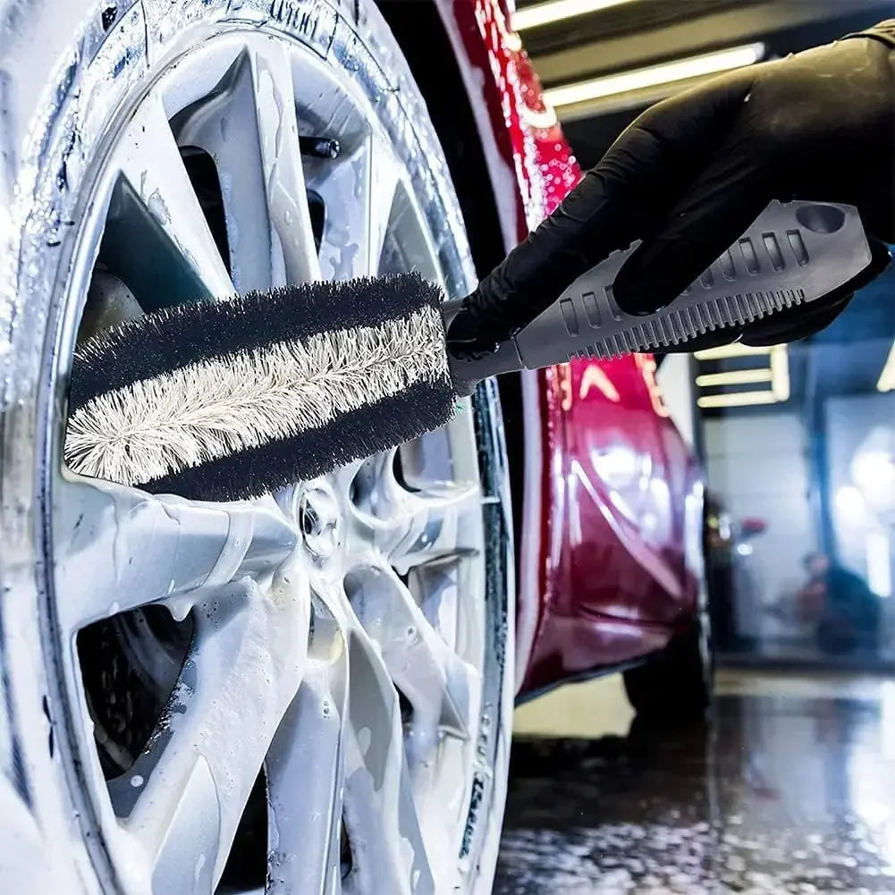 Long wheel brush from the 10-Piece Car Detailing Kit cleaning between the spokes of a soapy alloy wheel