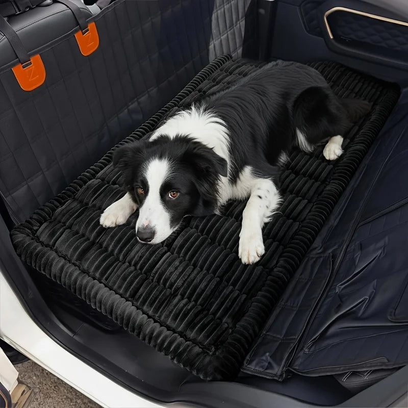 Black and white border collie lying on the black Plush Car Dog Bed covering a car back seat footwell