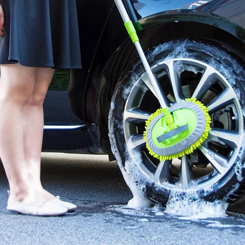 Person cleaning a car wheel with a green brush