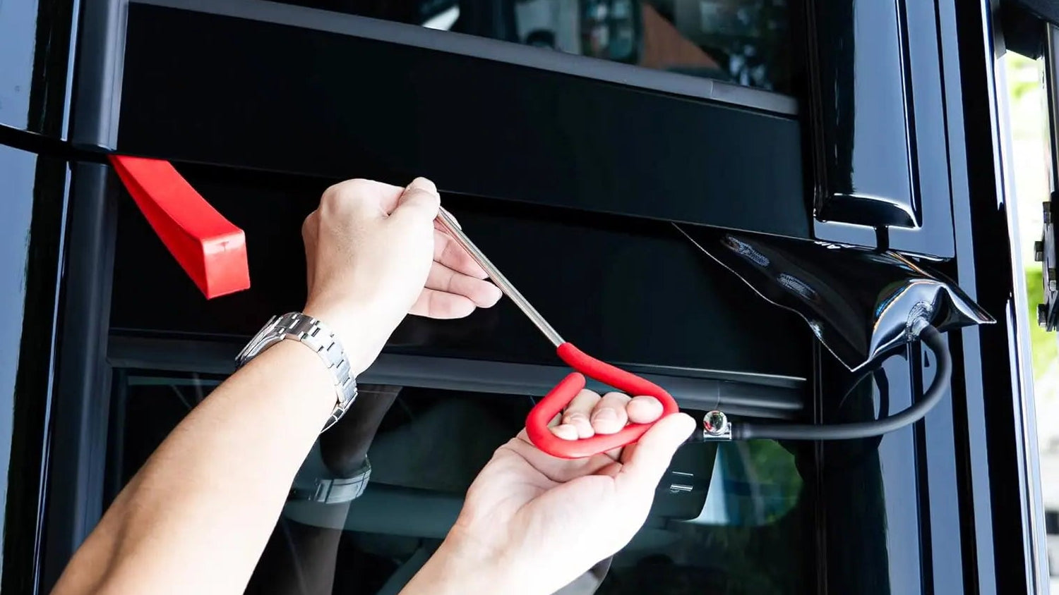 Person using a tool to cut car window film with an orange guide showing correct technique.