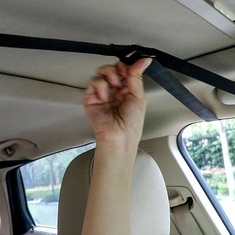 Hand threading the Soft Roof Rack Pads' tie-down strap through a car's rear door gap to secure it inside the cabin