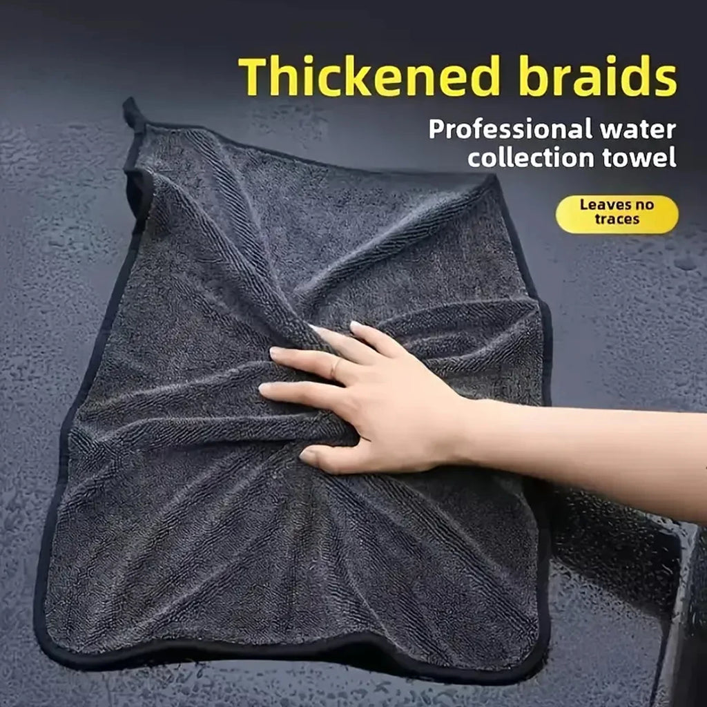 Hand pressing into a wet, twisted microfibre car drying towel on a car surface, professional water-collection towel