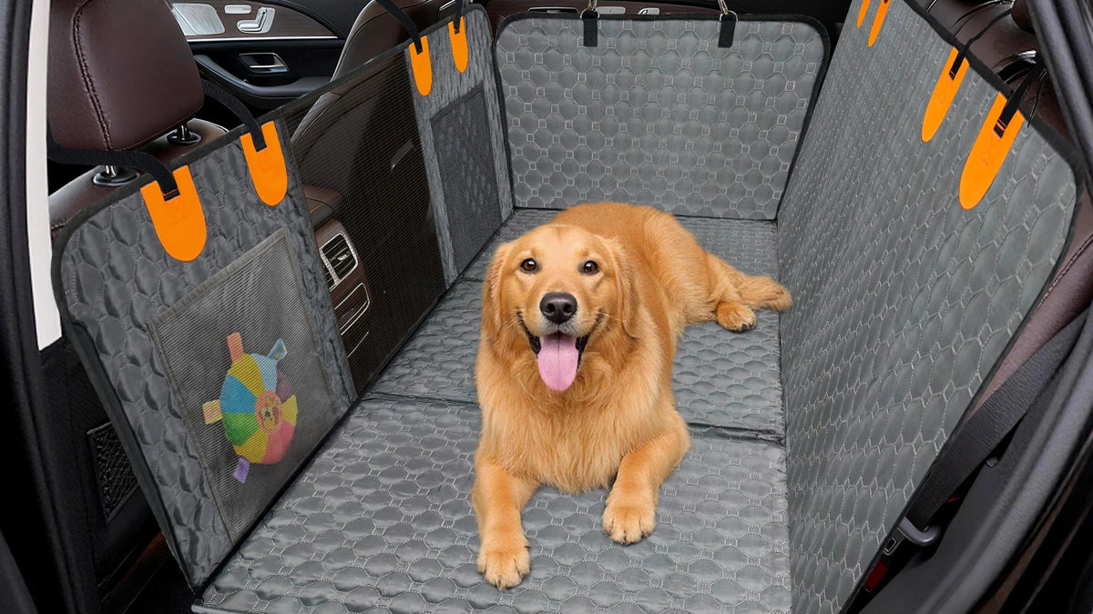 Dog lying on a gray car seat cover with orange straps in a vehicle.