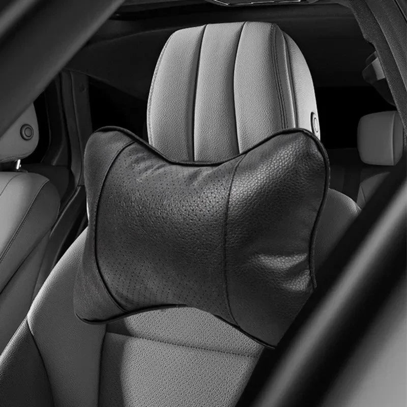 Black car neck support cushion on seat headrest illuminated by warm interior light