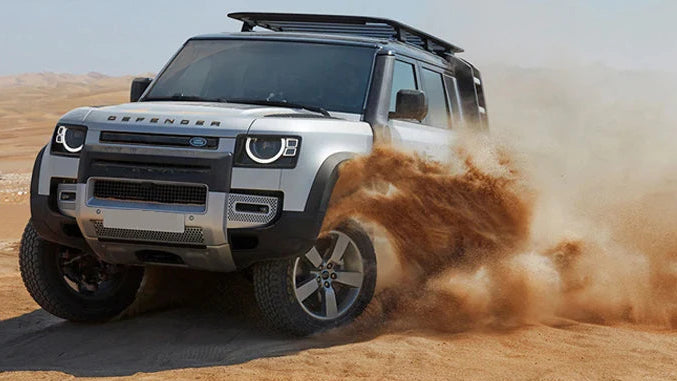 Silver SUV driving on sand with a red tire track device showing measurements below.