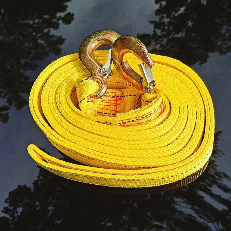 Coiled yellow heavy-duty tow strap with bronze-finish safety hooks outdoors