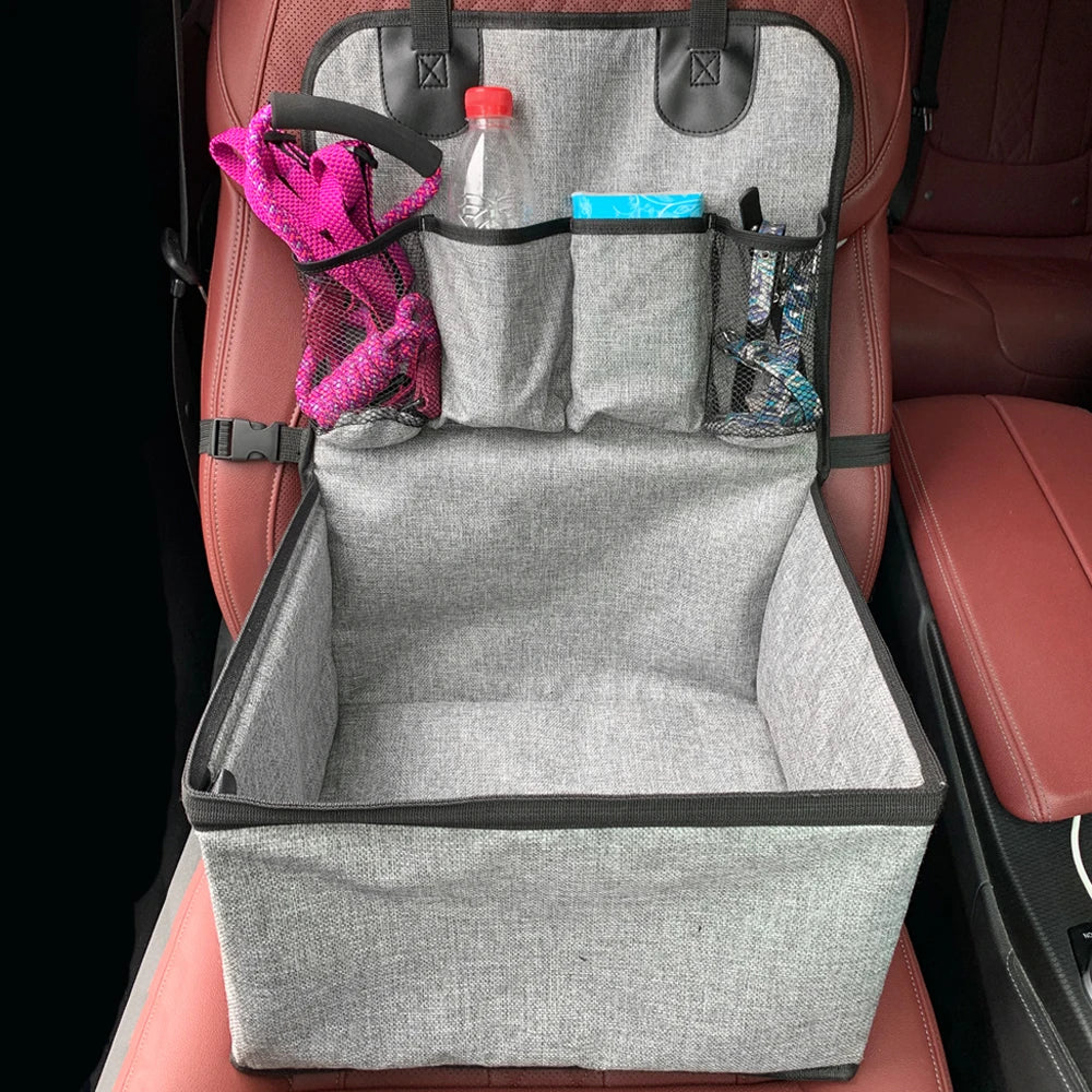 Empty foldable dog car booster seat strapped onto a car front seat with hanging pet accessory pouches for toys and leads.