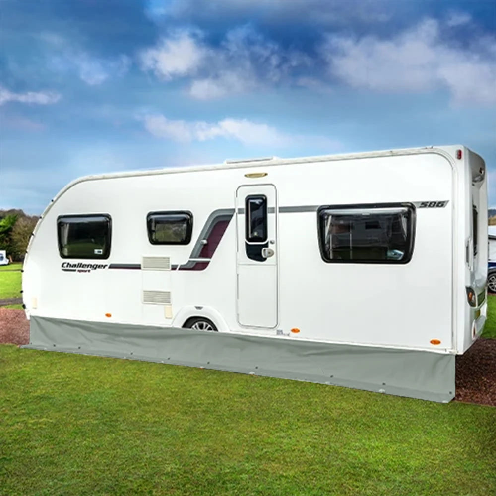White touring caravan with the grey Caravan Awning Draught Skirt fitted along its full length, on a grassy pitch under blue sky