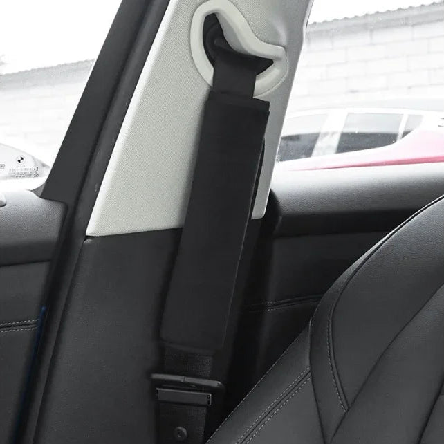 Black seat belt shoulder cover fitted to a door-mounted seat belt anchor inside a parked car