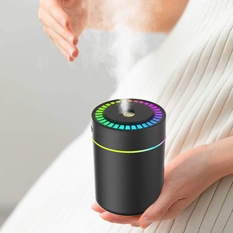 Close-up of a black car aroma diffuser emitting mist while held in someone's hands