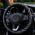 Black and white diamond pattern linen steering wheel cover fitted on a car steering wheel viewed against a green outdoor background