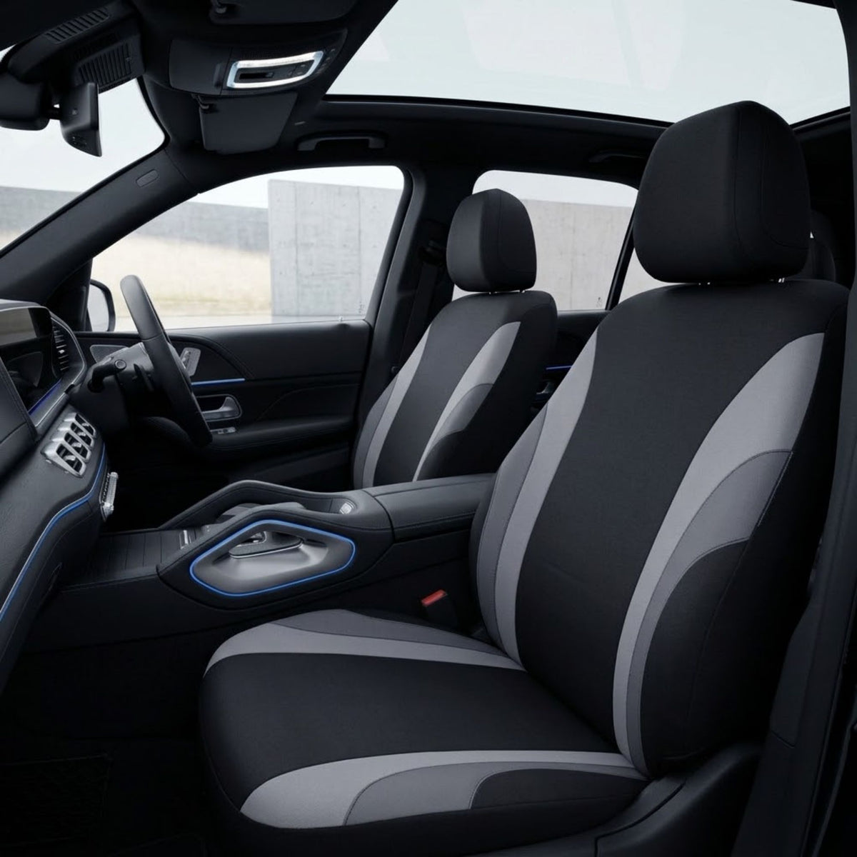 Black and gray car seat covers installed on the front seats of a vehicle interior, shown from the side with the dashboard, steering wheel, and windows visible.