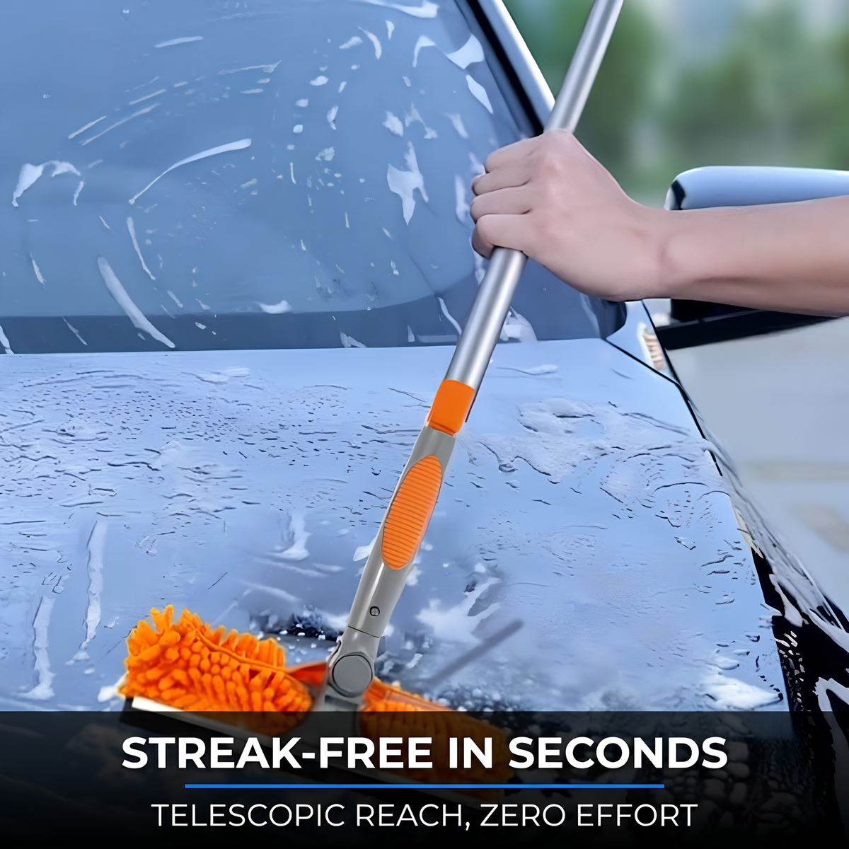 A hand holds a long-handled microfiber car cleaner with an orange grip and silver telescopic pole, cleaning a wet car windshield. Text at the bottom reads 'STREAK-FREE IN SECONDS' and 'TELESCOPIC REACH, ZERO EFFORT'.