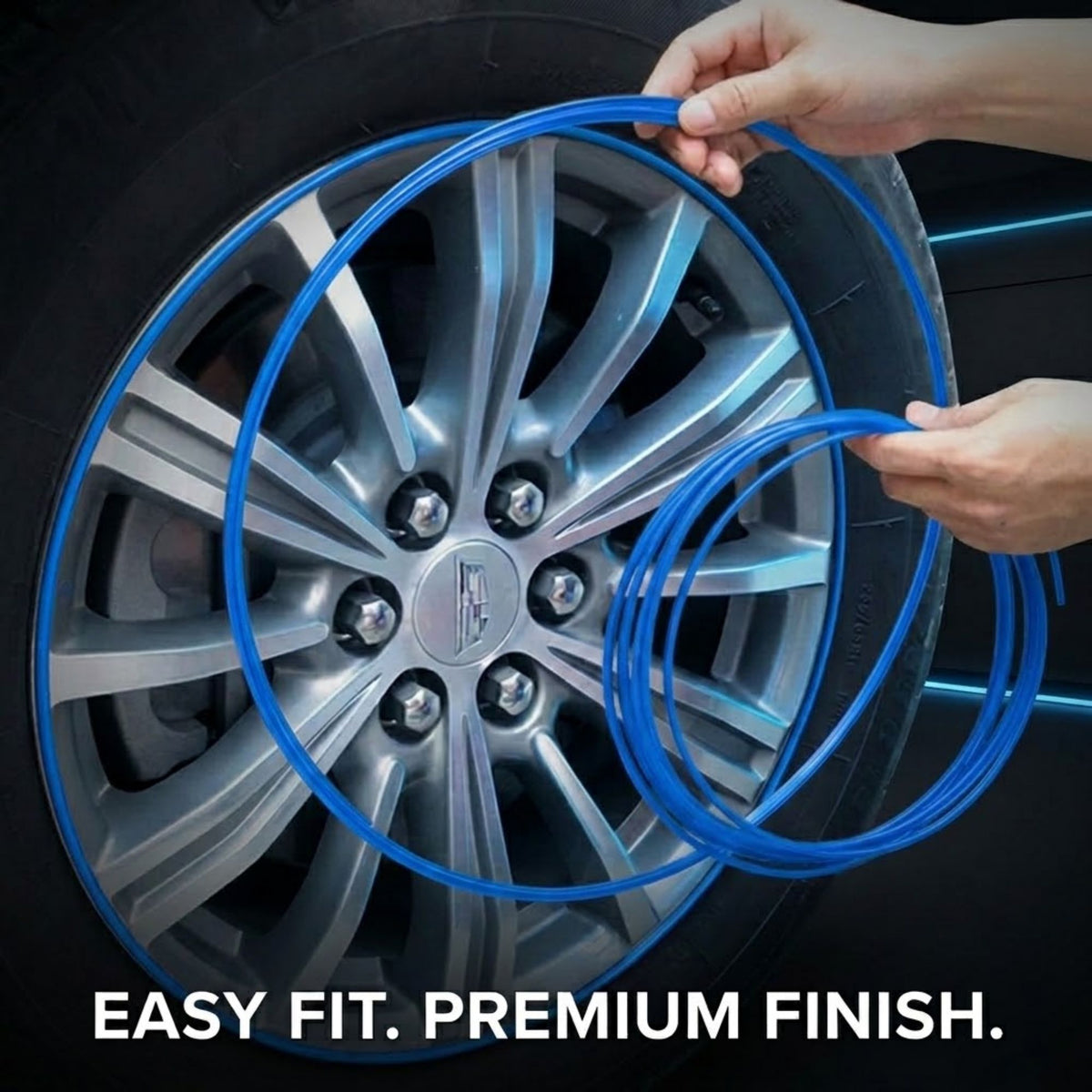 Blue self-adhesive tire liner being applied to a silver alloy car wheel by hands, with the text 'EASY FIT. PREMIUM FINISH.