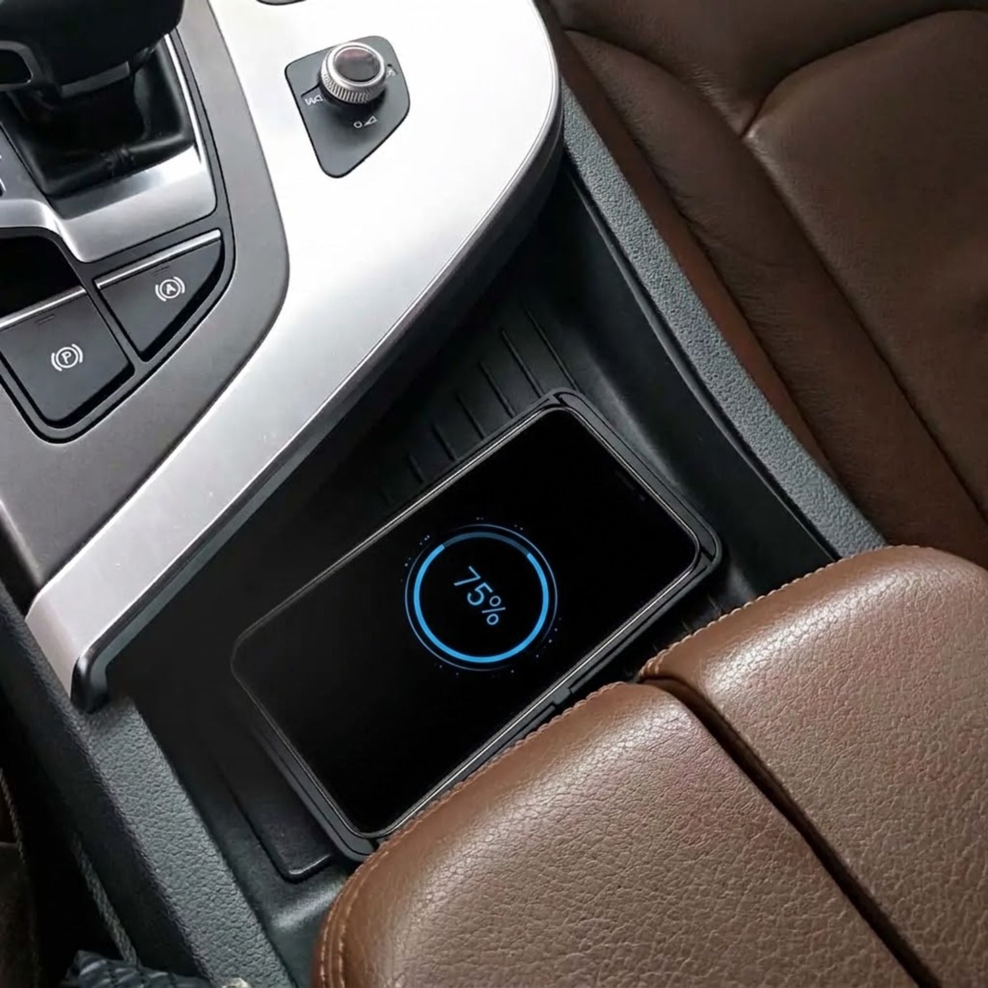 A black rectangular wireless phone charger pad with a glowing blue 75% battery indicator, placed in a car's center console next to brown leather seats.