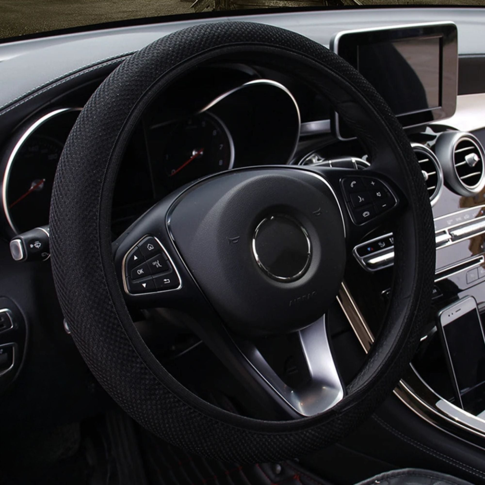 Black mesh steering wheel cover fitted on car dashboard view, lightweight low-profile design