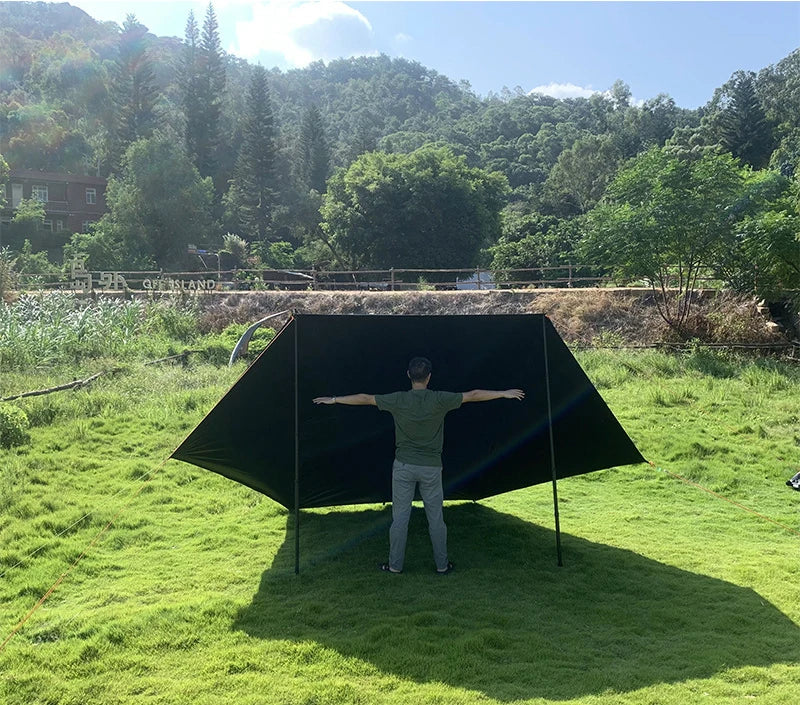 A person standing under the assembled black car side awning, illustrating the height and overall dimensions of the 3-metre by 2-metre structure.