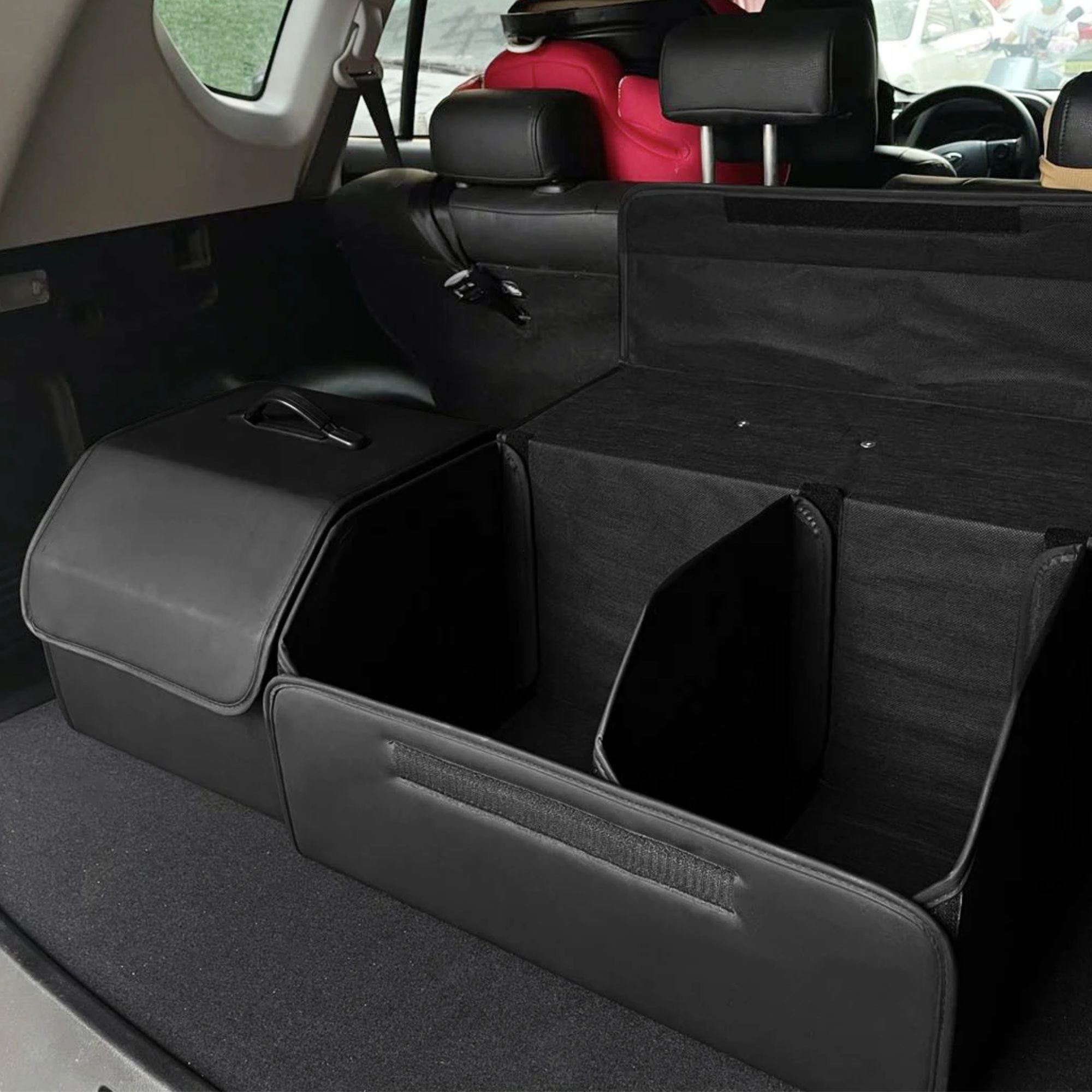 Close up view of an open black leather car boot organiser revealing deep storage compartments and adjustable velcro dividers.