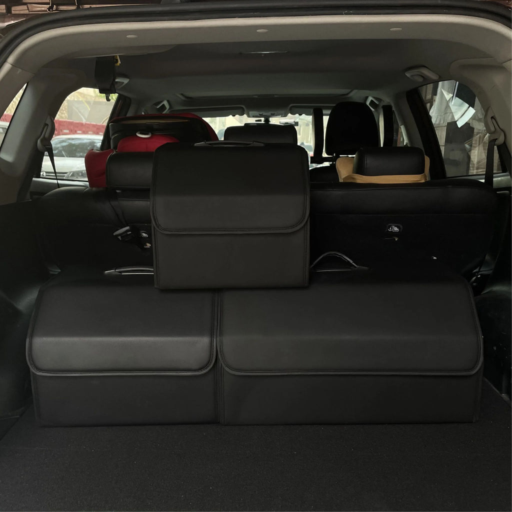 Three different sizes of black leather car boot organisers sitting side-by-side inside the boot of a luxury SUV, demonstrating relative scale.