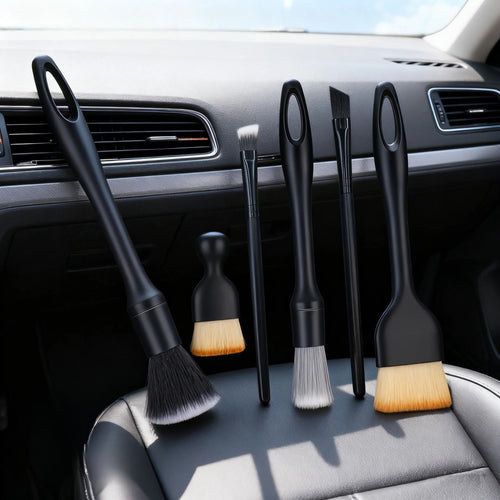 Assorted car detailing brushes resting on a black leather vehicle seat, demonstrating product scale and interior application.