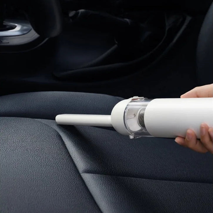 Cordless car vacuum cleaner using the targeted gap nozzle attachment to extract dust directly from a dark automotive seat seam.