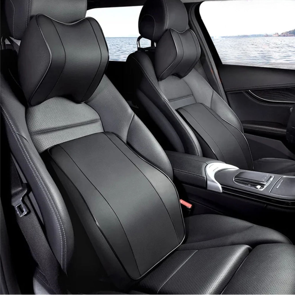 Black memory foam neck headrest and lumbar support pillow installed on a black vehicle seat.
