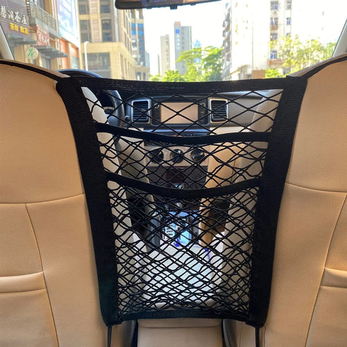 A black stretchable mesh organiser installed between the two front seats of a vehicle, viewed from the rear passenger cabin.