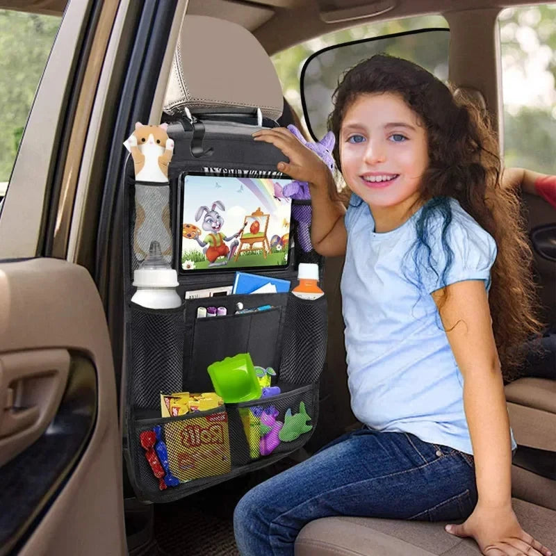 Child sitting in a vehicle backseat viewing a tablet secured inside the clear PVC window of the car seat organiser.