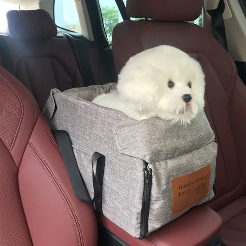 Ash grey pet carrier mounted directly on a vehicle centre armrest with a small dog secured inside.