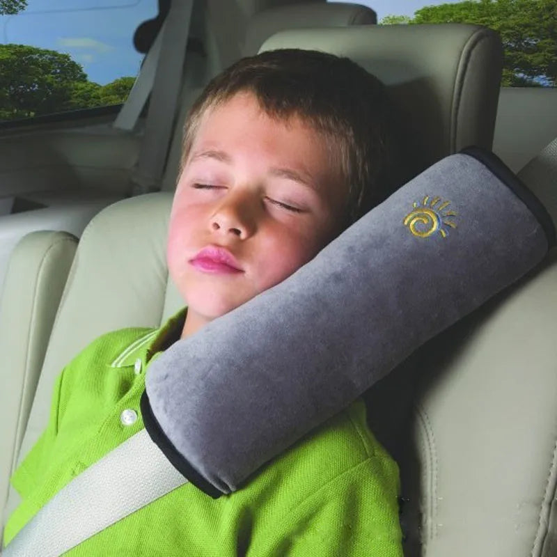 Young boy sleeping in a vehicle with his head resting on the heather grey seat belt shoulder pad.