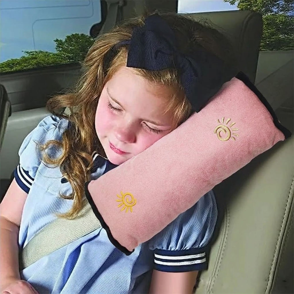 Young girl sleeping in a car with her head supported by the soft pink seat belt shoulder pad.