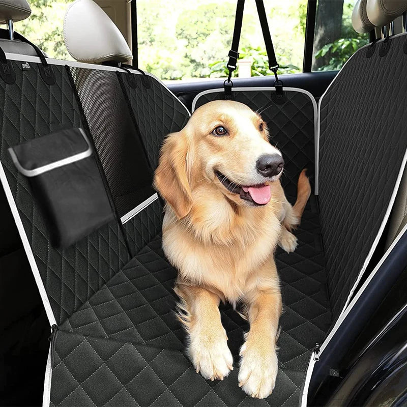 Golden Retriever sitting safely on a black dog car backseat cover installed in the rear of a vehicle.