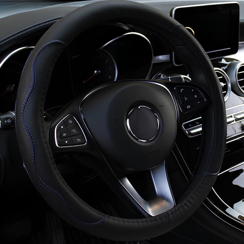 Black embossed PU leather steering wheel cover featuring blue stitching trim installed on a steering wheel inside a vehicle cabin.