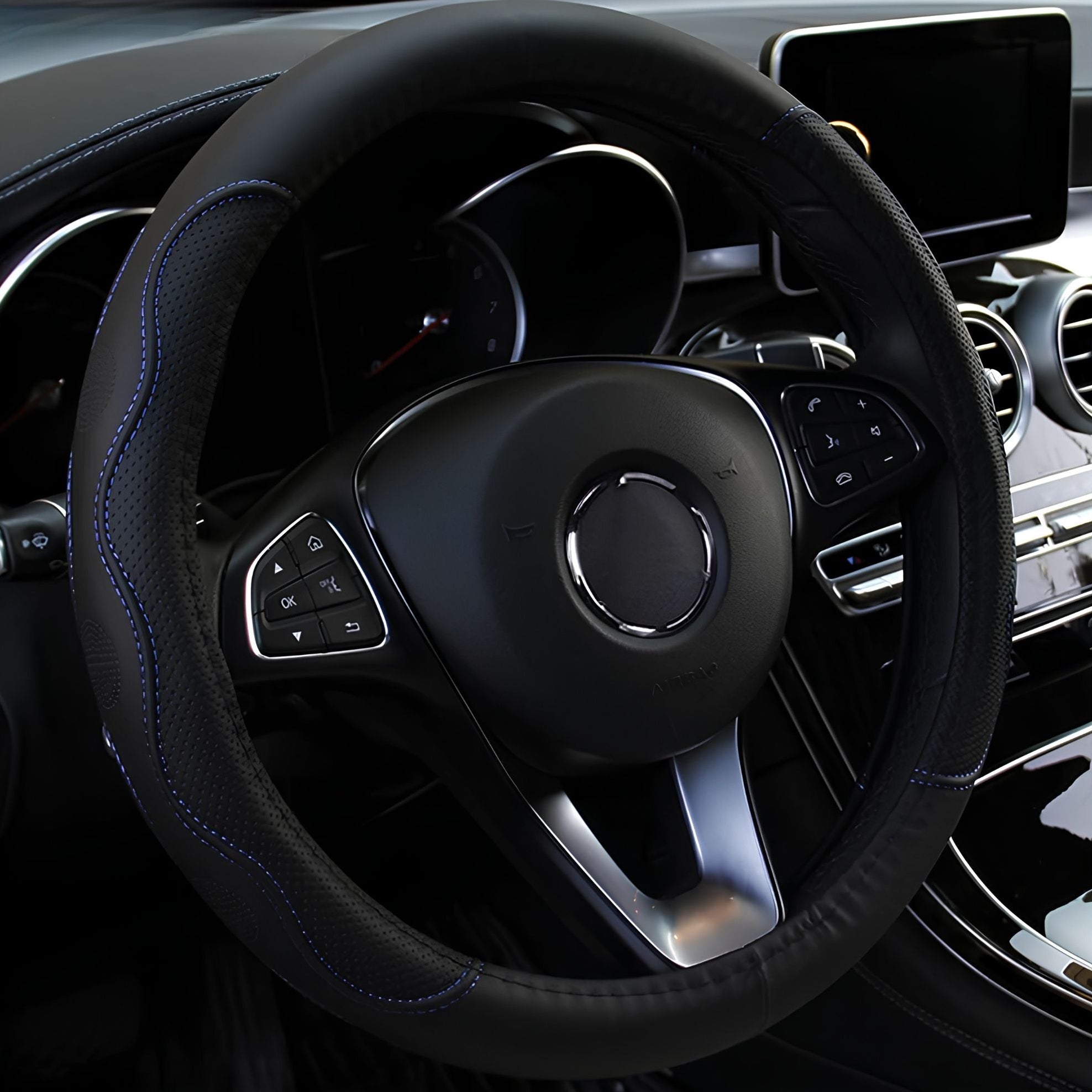 Black embossed PU leather steering wheel cover featuring blue stitching trim installed on a steering wheel inside a vehicle cabin.