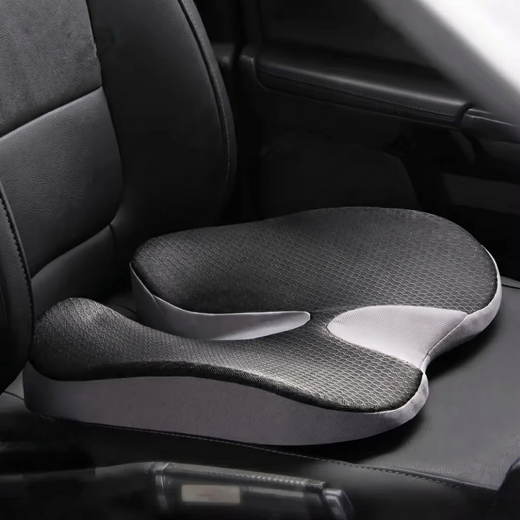 Black ergonomic memory foam driving cushion resting naturally on a black leather car seat.
