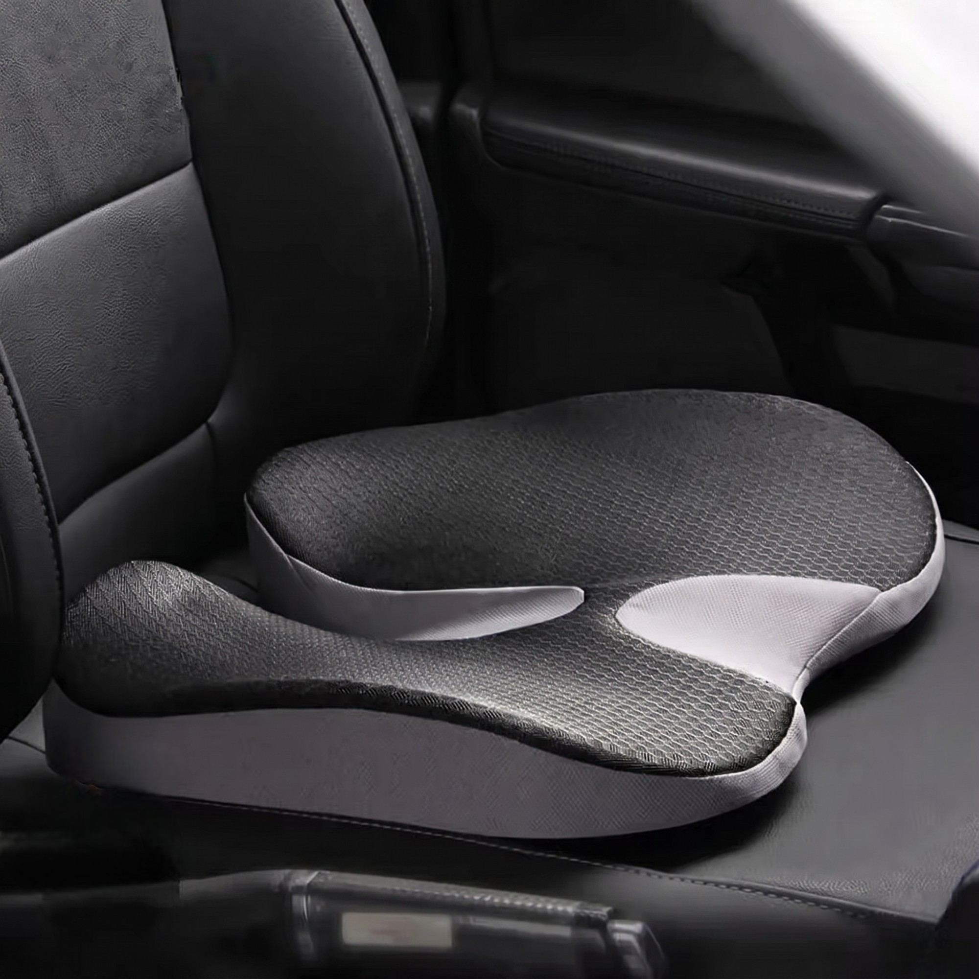 Black ergonomic memory foam driving cushion resting naturally on a black leather car seat.