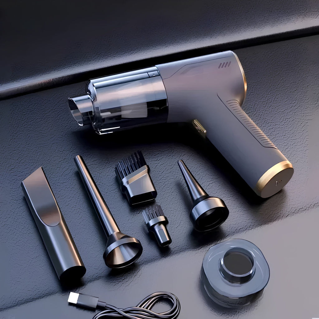 Black handheld car vacuum cleaner laid flat on a dark surface, providing a close-up view of the ABS material finish alongside its interchangeable cleaning nozzles.