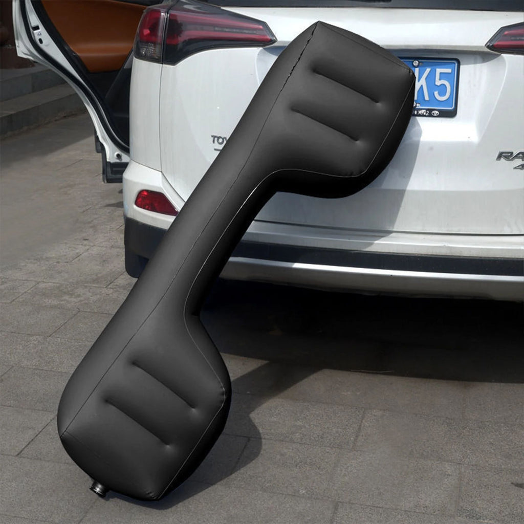 The large, fully inflated black backseat gap blocker leaning against the rear bumper of a white SUV outdoors to demonstrate its real-world scale and durable exterior material.
