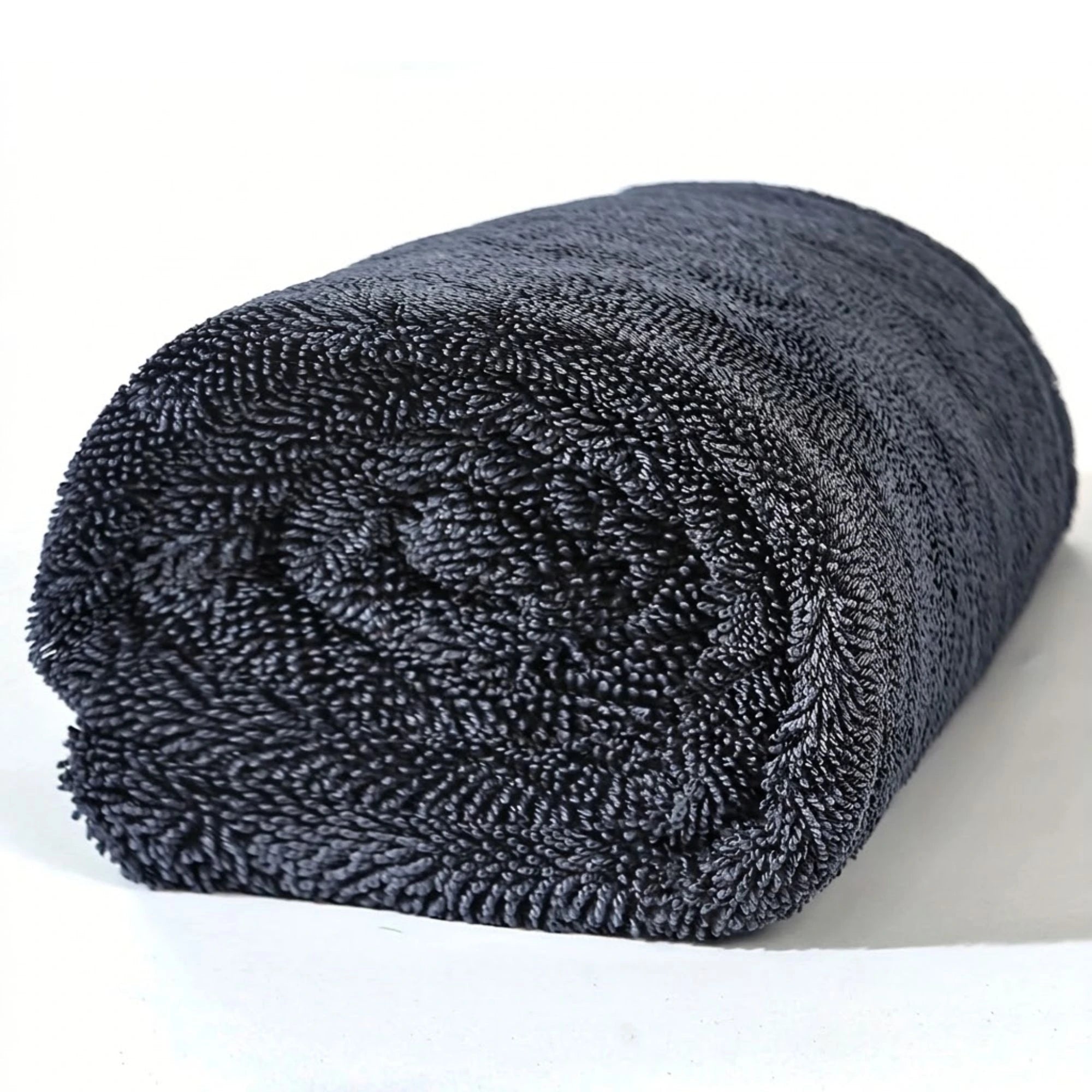 Rolled up dark grey XXL Microfiber Drying Towel on a white background