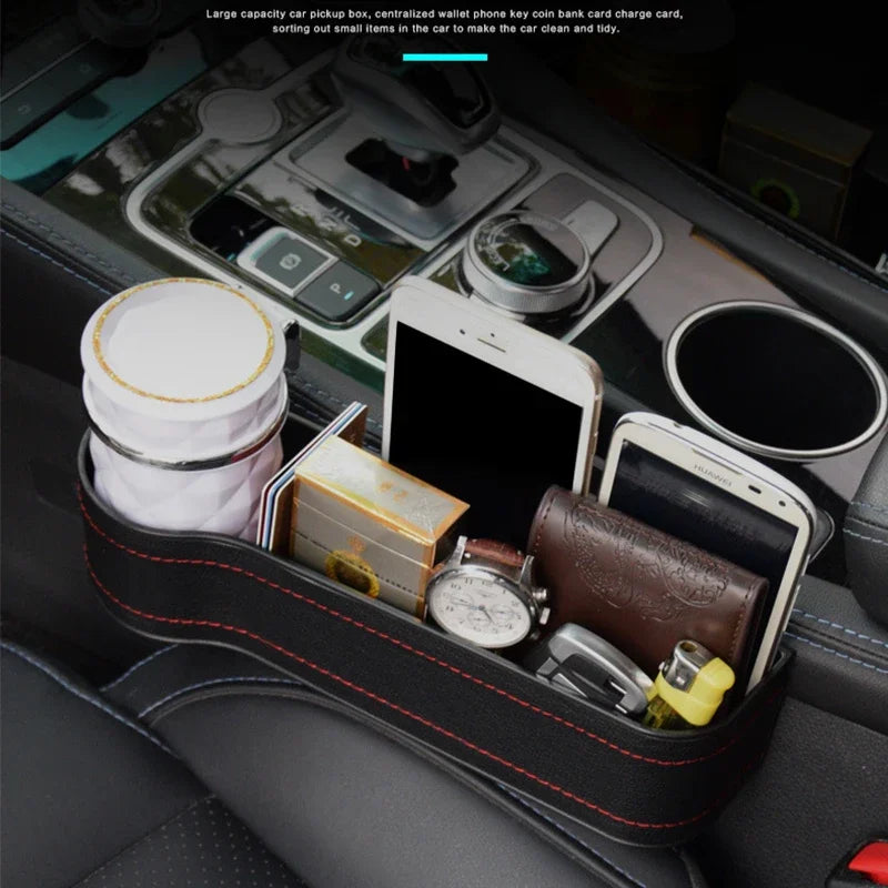 Close-up of a black car seat crevice storage box installed on the passenger side, securely holding a smartphone, wallet, and accessories.