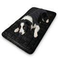 Black and white border collie lying on the black Plush Car Dog Bed covering a car back seat footwell