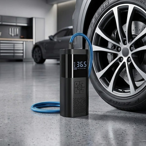 Cordless digital tyre inflator resting on a clean concrete floor in a modern, well-lit luxury garage next to the tire of a high-end SUV.