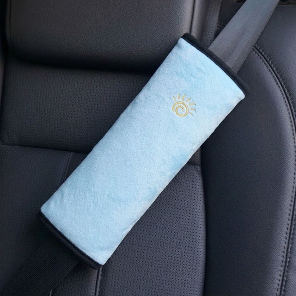 Sky blue kids seat belt shoulder pad installed on a black vehicle seat belt.