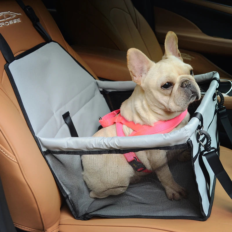 Grey small dog car seat carrier installed in a vehicle with a French Bulldog inside wearing a pink harness.