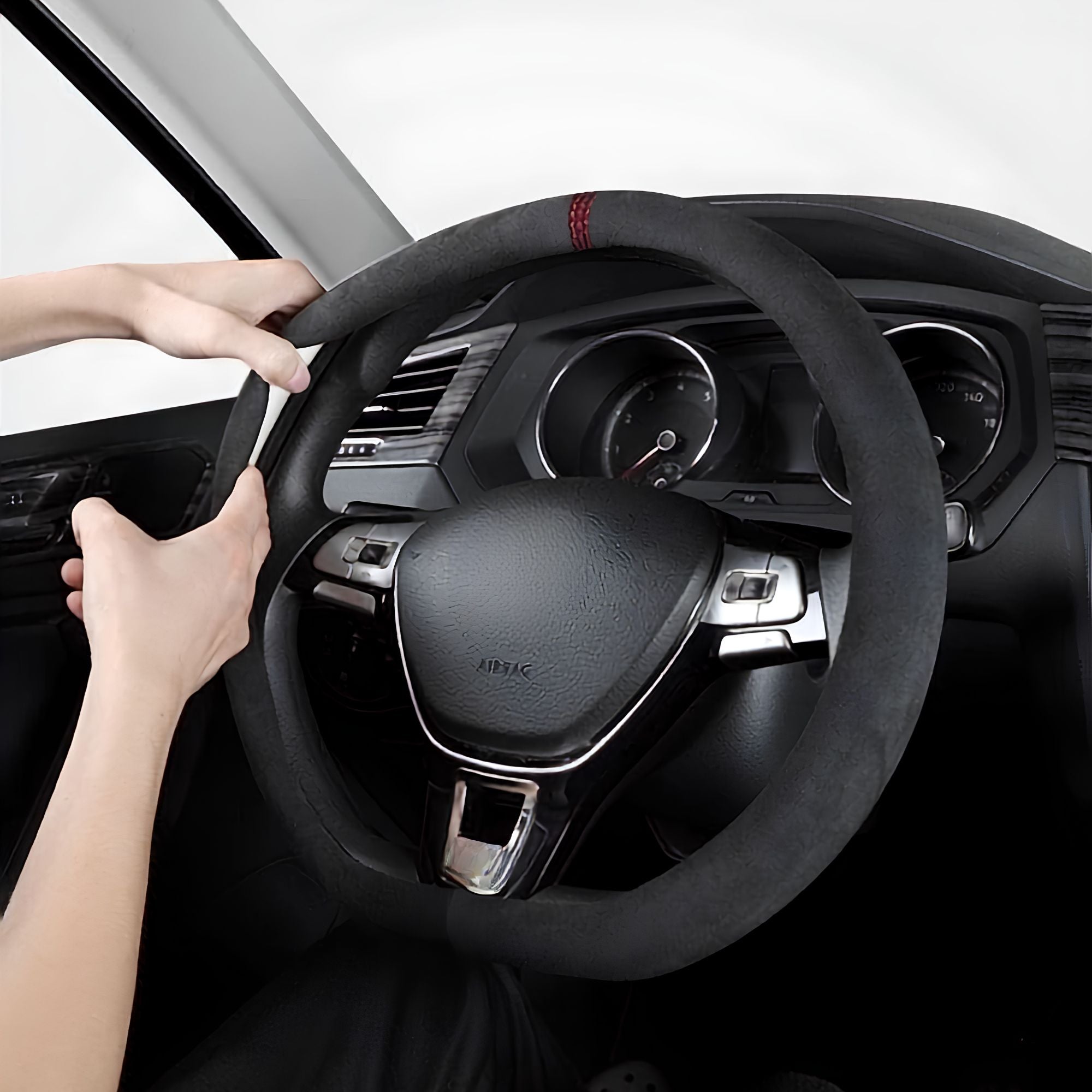 Hands fitting the black Steering Wheel Cover and Non-Slip Suede Grip Cover with red stitching onto a car steering wheel.