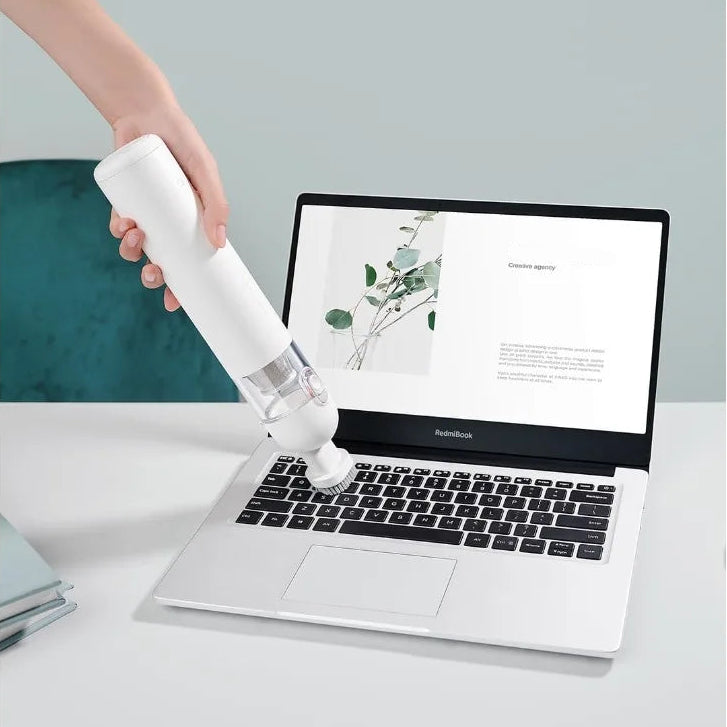Portable mini dust collector using the interchangeable bristle brush suction nozzle to clean fine particulate matter from a laptop keyboard.