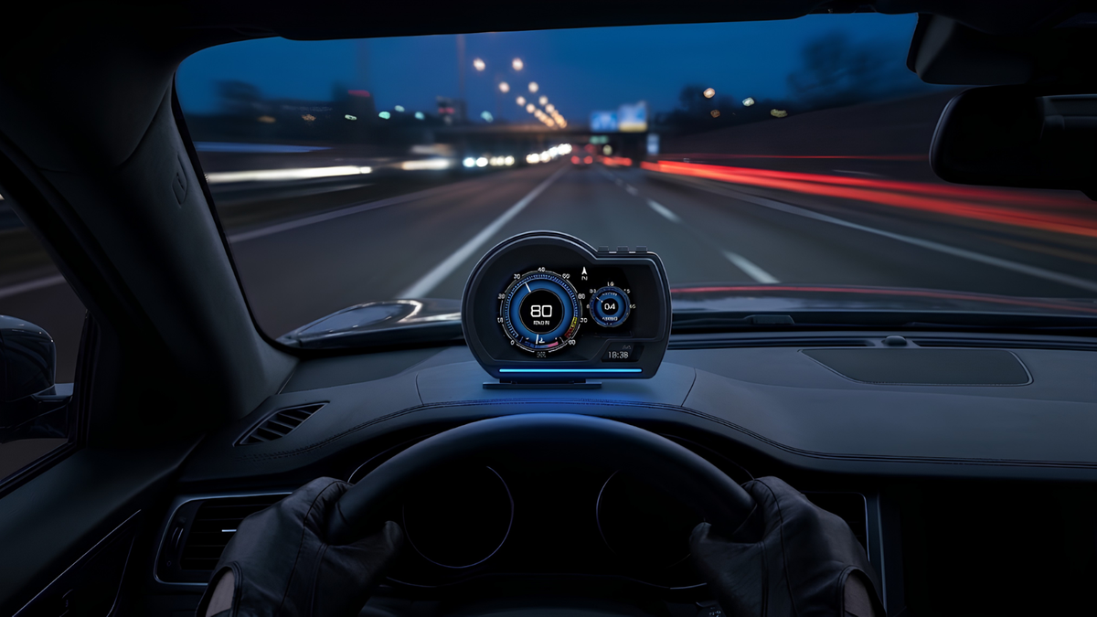 A car's digital head-up display showing speed and navigation on the dashboard, with a driver's gloved hands on the steering wheel inside a car at night.